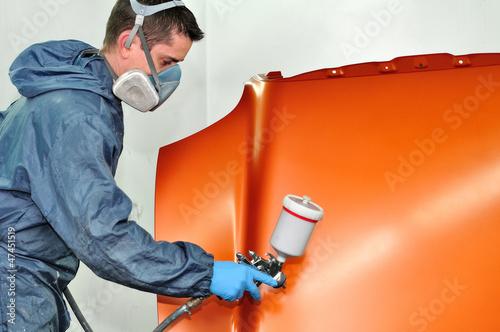 Photo: Worker painting orange car bonnet. Worker painting orange car bonnet.
