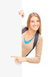 Smiling female student pointing on a blank panel