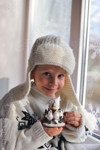 Photo: winter boy sitting by the window in a white knitted cap winter boy sitting by the window in a white knitted cap