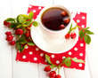 cup of tea with hip roses, on wooden table