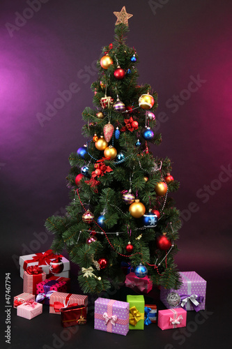 Photo: Decorated Christmas tree with gifts on dark color background Decorated Christmas tree with gifts on dark color background