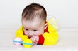 Portrait of the sad baby with a rattle (2,5 months)