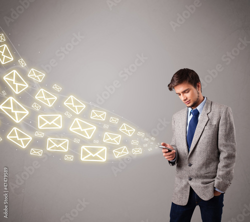 Photo: attractive young man holding a phone with message icons attractive young man holding a phone with message icons