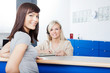 Woman With Receptionist Filling Form At Dentist's Office
