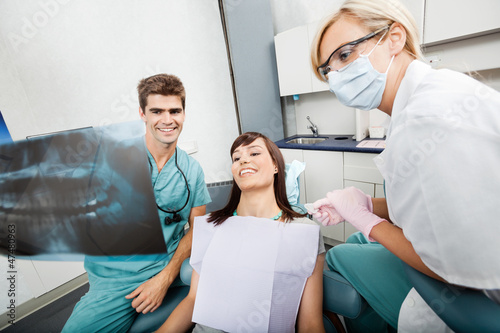 Photo: Dentist With Female Assistant Showing X-Ray Image To Patient Dentist With Female Assistant Showing X-Ray Image To Patient