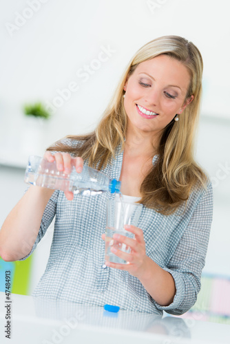 Photo: junge frau schenkt ein glas wasser ein junge frau schenkt ein glas wasser ein