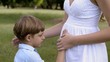 Happy pregnant mother with son leaning head on tummy