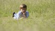 Young school boy doing homework alone, lying on grass