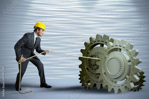 Foto: Businessman turning a gear system Businessman turning a gear system