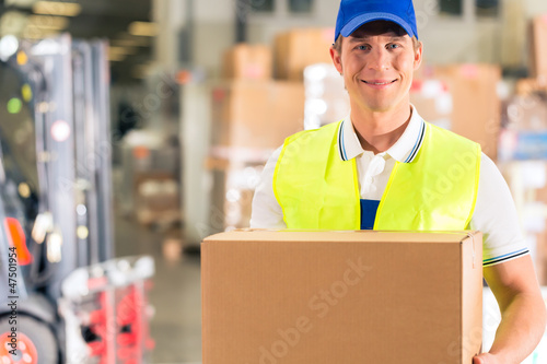Photo: Lagerist von Spedition hält Paket in einem Lager Lagerist von Spedition hält Paket in einem Lager