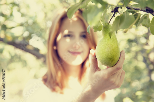 Photo: Redhead girl holding pear in garden Redhead girl holding pear in garden