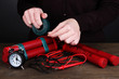 Human makes timebomb on wooden table on black background