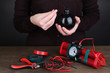 Human makes timebomb on wooden table on black background
