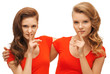 two teenage girls showing hush gesture