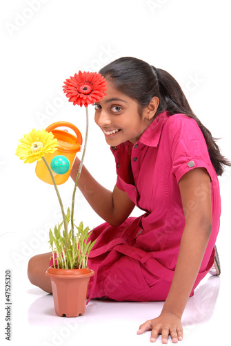 Photo: Beautiful young girl watering a plant Beautiful young girl watering a plant