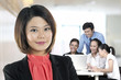 Photo: Beautiful Chinese Business woman with colleagues working behind. Beautiful Chinese Business woman with colleagues working behind.