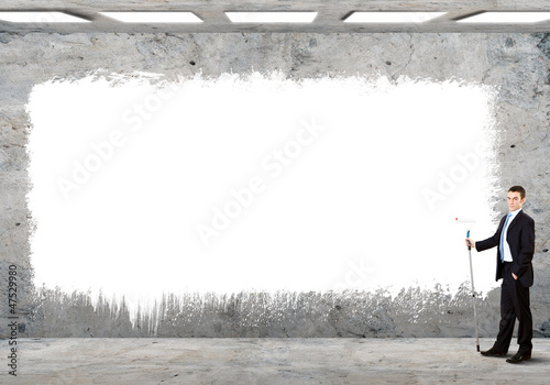 Photo: Business person standing near a blank billboard Business person standing near a blank billboard