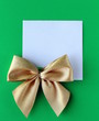 Foto: white blank with a gold bow on a green background white blank with a gold bow on a green background