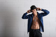 Photo: Young man with ear-phones dancing against white brick wall. Young man with ear-phones dancing against white brick wall.
