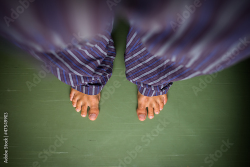 Photo: Alone in the house: man in pyjamas looking down on his bare feet Alone in the house: man in pyjamas looking down on his bare feet