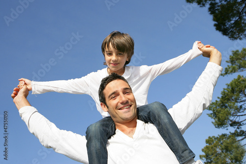 Photo: Little boy riding on his father's shoulders Little boy riding on his father's shoulders