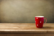 Red cup with dots on wooden table over grunge background