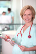 Foto: Medic wearing stethoscope examining patient's chart Medic wearing stethoscope examining patient's chart