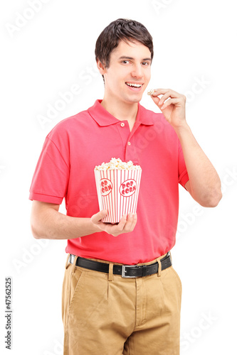 Photo: Young smiling man eating popcorn Young smiling man eating popcorn