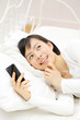 スマートフォンを寝ながら使う女の子