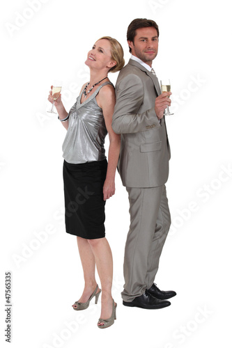Photo: Couple stood back to back holding champagne glasses Couple stood back to back holding champagne glasses