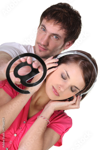 Photo: Woman listening to music and a man with an at symbol Woman listening to music and a man with an at symbol