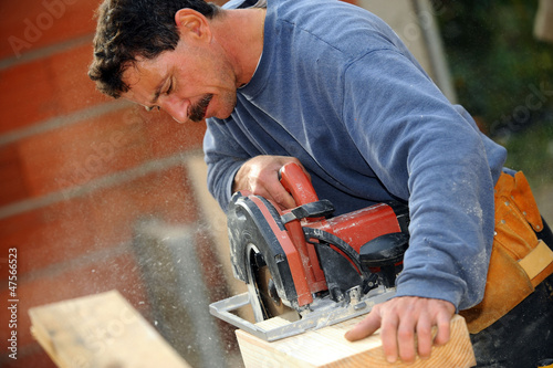 Photo: Man cutting block of wood to size using circular saw Man cutting block of wood to size using circular saw
