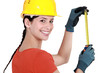 Young female laborer using measuring tape