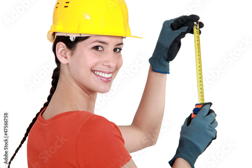Photo: Young female laborer using measuring tape Young female laborer using measuring tape