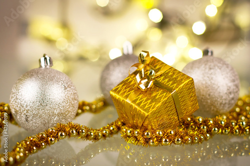 Photo: Christmas gift and baubles over shiny lights background Christmas gift and baubles over shiny lights background