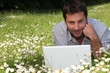Man working on laptop in the daisies