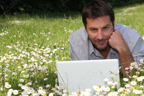 Photo: Man working on laptop in the daisies Man working on laptop in the daisies