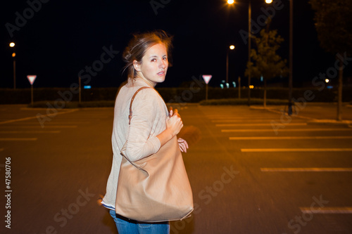 Photo: Scared woman running from her pursuer in a deserted parking Scared woman running from her pursuer in a deserted parking