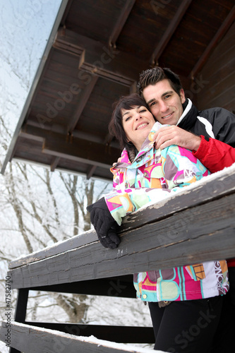 Photo: Couple stood by snow covered chalet Couple stood by snow covered chalet