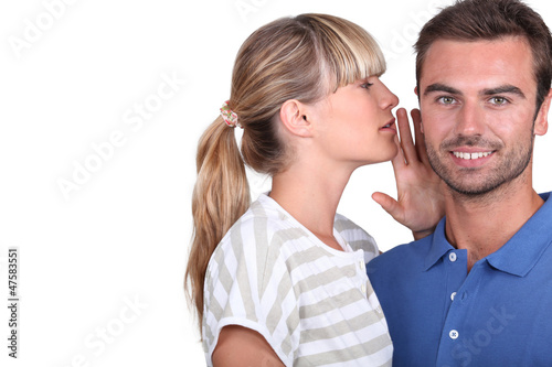 Photo: Young woman whispering into her boyfriend's ear Young woman whispering into her boyfriend's ear