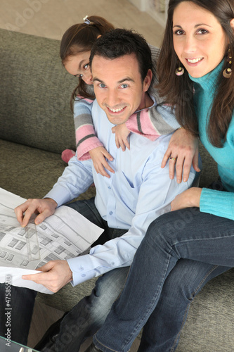 Photo: Young family relaxing on sofa with newspaper Young family relaxing on sofa with newspaper