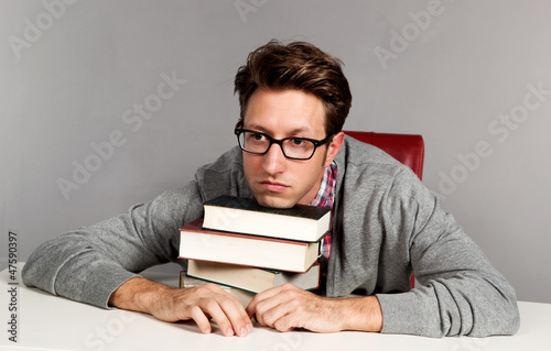 Photo: Erschöpfter junger Mann liegt auf seinen Büchern Erschöpfter junger Mann liegt auf seinen Büchern