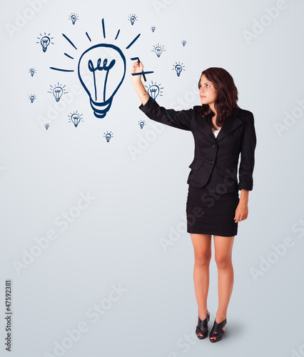 Photo: Woman drawing light bulb on whiteboard Woman drawing light bulb on whiteboard