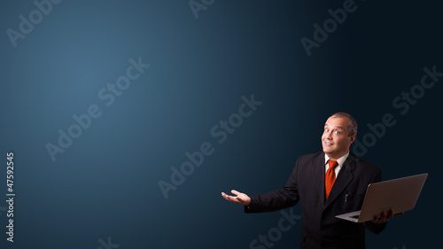 Photo: businessman holding a laptop and presenting copy space businessman holding a laptop and presenting copy space