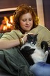Photo: Smiling teenage girl fondling cat at home Smiling teenage girl fondling cat at home
