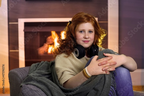 Photo: Teenage girl sitting at home at fireplace Teenage girl sitting at home at fireplace