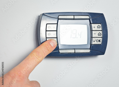 Photo: Finger pushing thermostat control button Finger pushing thermostat control button