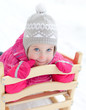Portrait of cute little girl sitting in sled