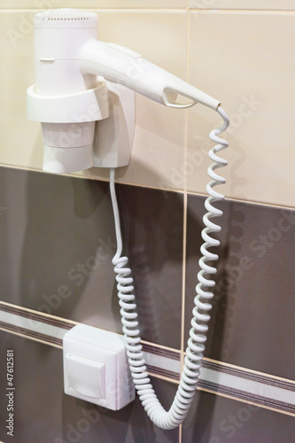 Photo: White Hair Dryer on wall in bathroom. White Hair Dryer on wall in bathroom.