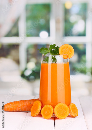 Photo: Glass of carrot juice on wooden table, on window background Glass of carrot juice on wooden table, on window background